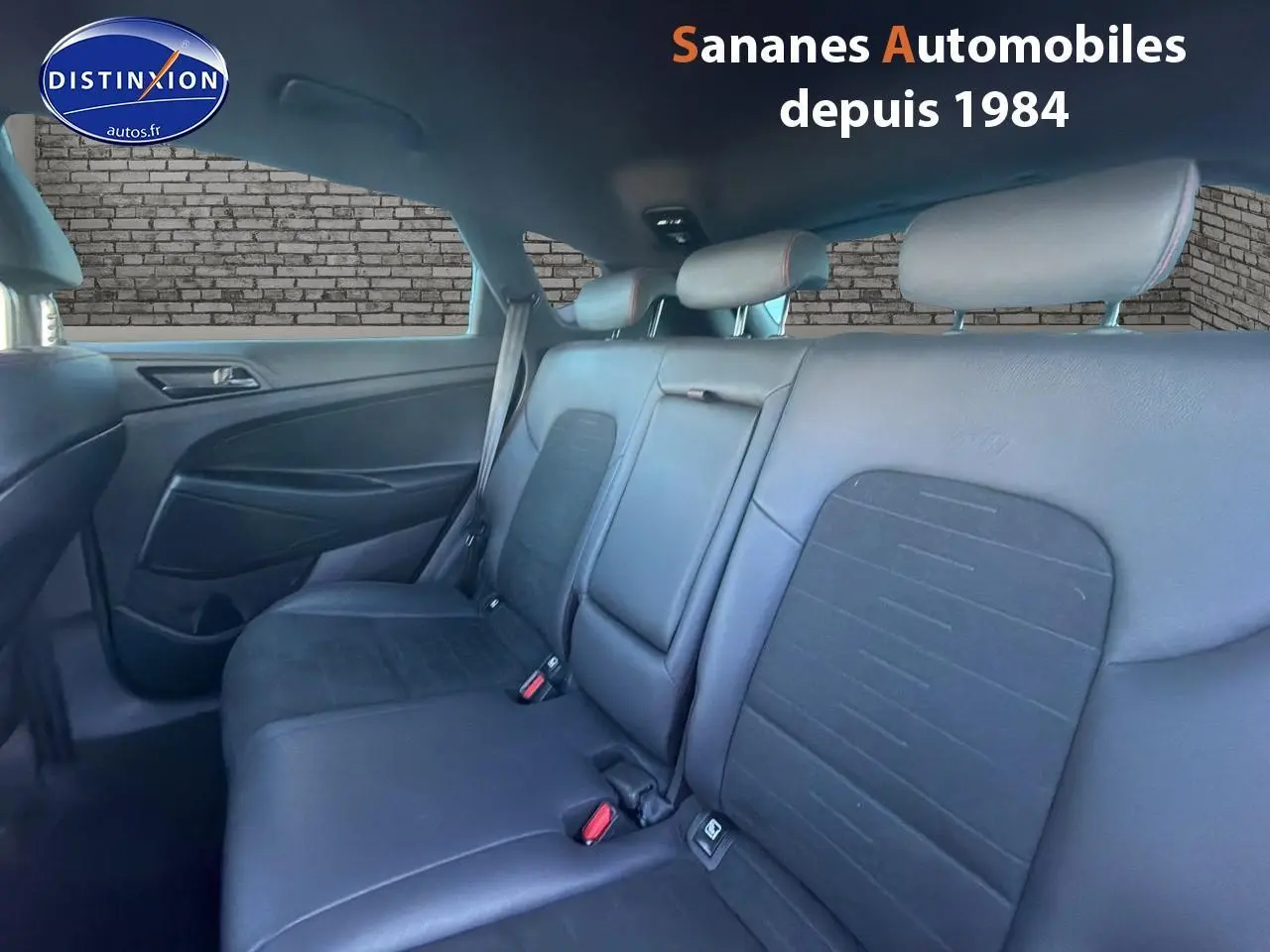 Vue intérieure arrière du Hyundai Tucson 1.6 Hybrid 136 N Line 2020, montrant les sièges cuir/alcantara gris foncé avec surpiqûres rouges.