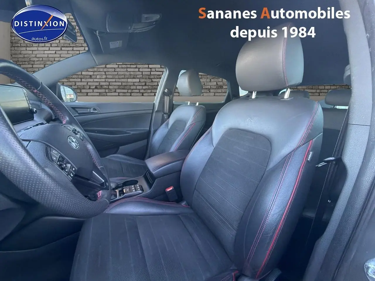 Vue intérieure côté conducteur du Hyundai Tucson N Line 2020, sièges cuir noir avec surpiqûres rouges visibles.