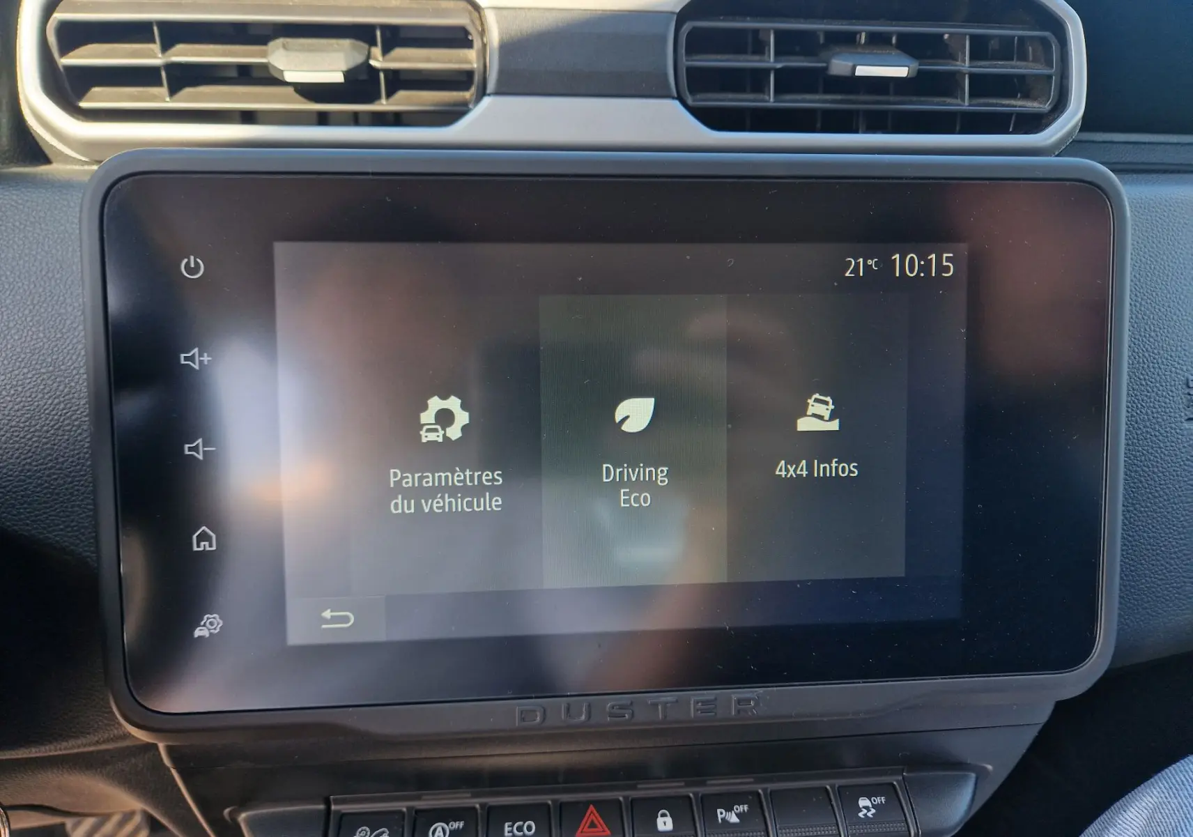 Écran tactile central du Dacia Duster 2024 blanc, affichant les paramètres véhicule et options 4x4, vue intérieure frontale.
