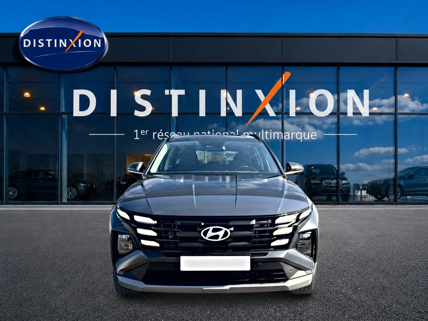 Vue avant d'un Hyundai Tucson 1.6 t-gdi 239 hybride gris ecotronic avec calandre noire et phares LED intégrés.