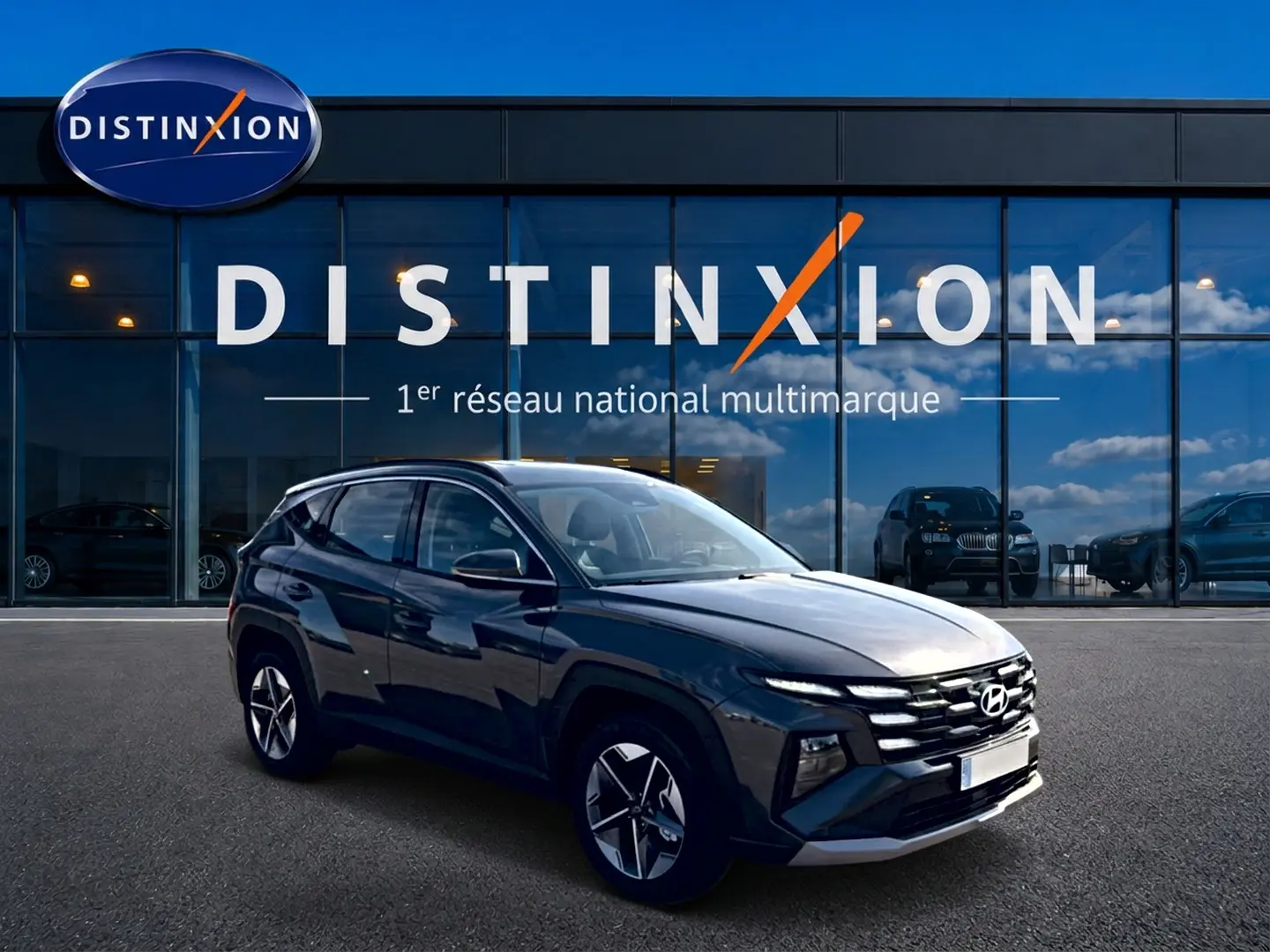Hyundai Tucson gris ecotronic en 3/4 avant droit, avec jantes alu et calandre distinctive, devant showroom Distinxion.