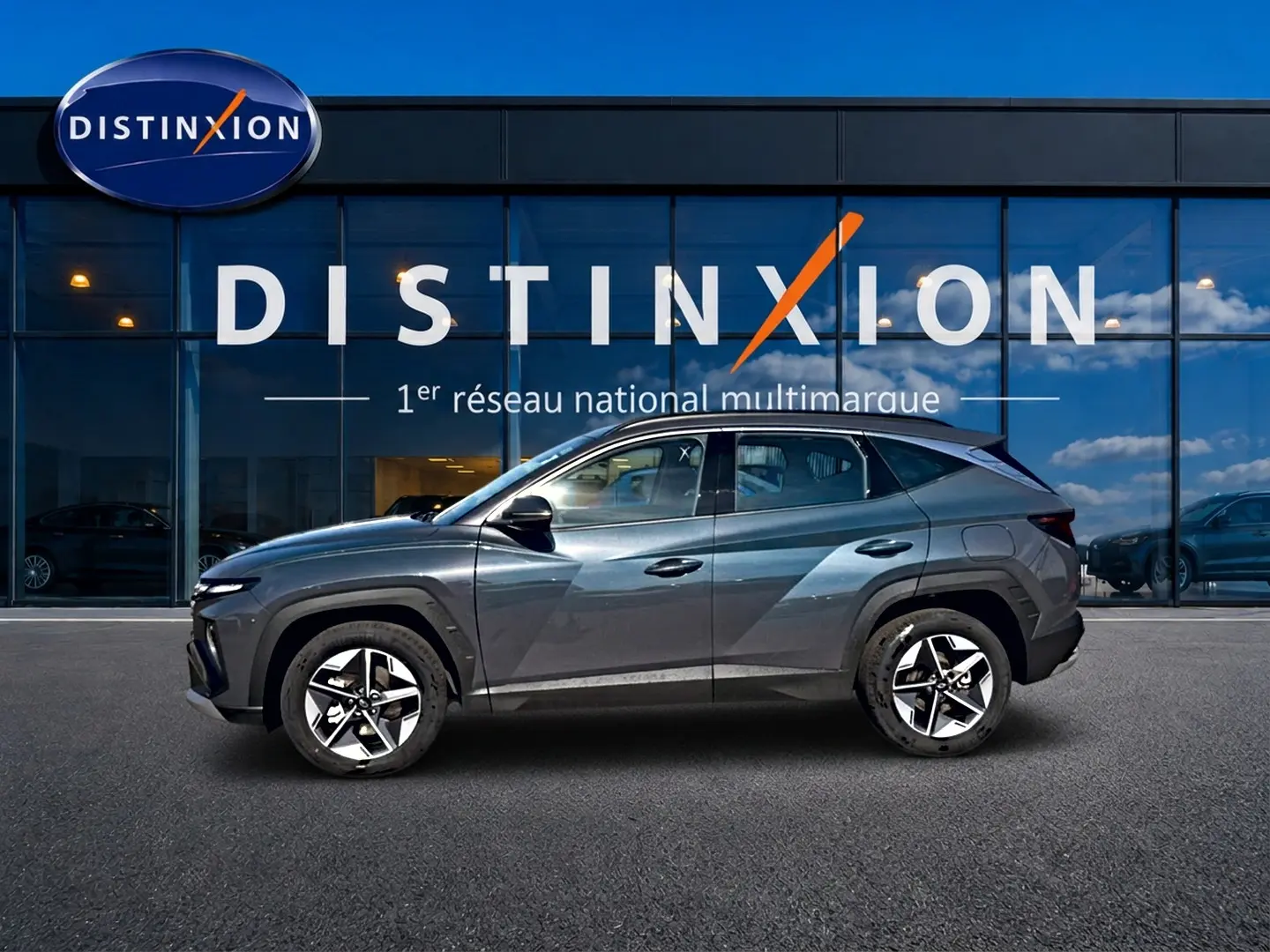 Vue de profil côté gauche d'un Hyundai Tucson gris ecotronic devant une vitrine avec logo Distinxion.