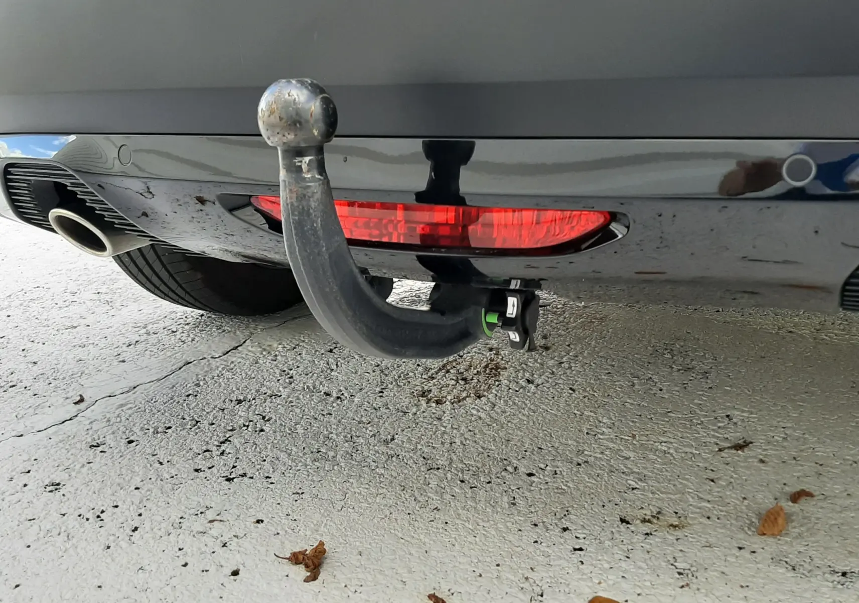 Gros plan sur l'attelage arrière noir d'une Citroën C4 gris 2024, avec feu antibrouillard intégré et sortie d'échappement visible.