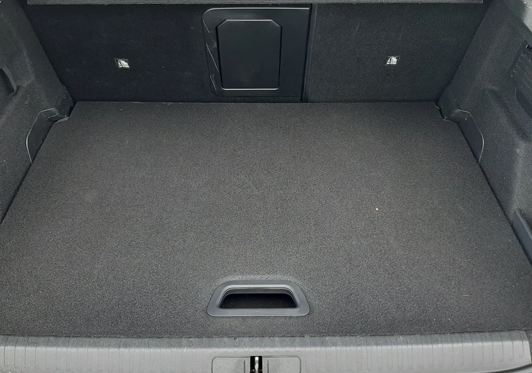 Vue plongeante sur le coffre spacieux et propre d’une Citroën C4 gris 2024, avec plancher plat et trappe arrière.