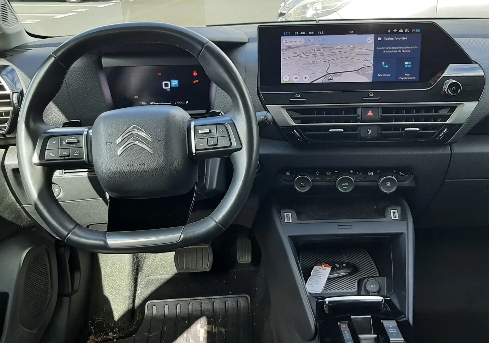 Intérieur noir de Citroën C4 2024, vue frontale du volant et tableau de bord avec écran tactile central allumé.