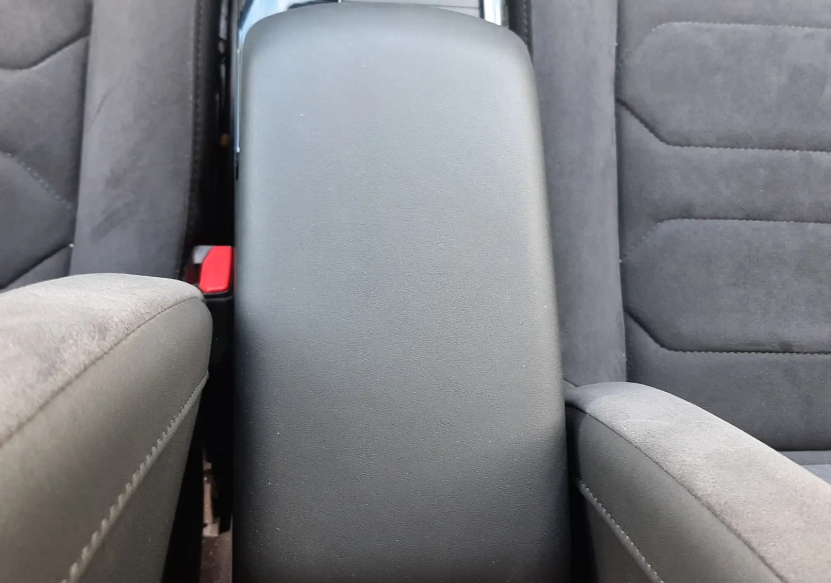Vue plongeante sur l'accoudoir central noir et les sièges en tissu gris foncé de la Citroën C4 2024.