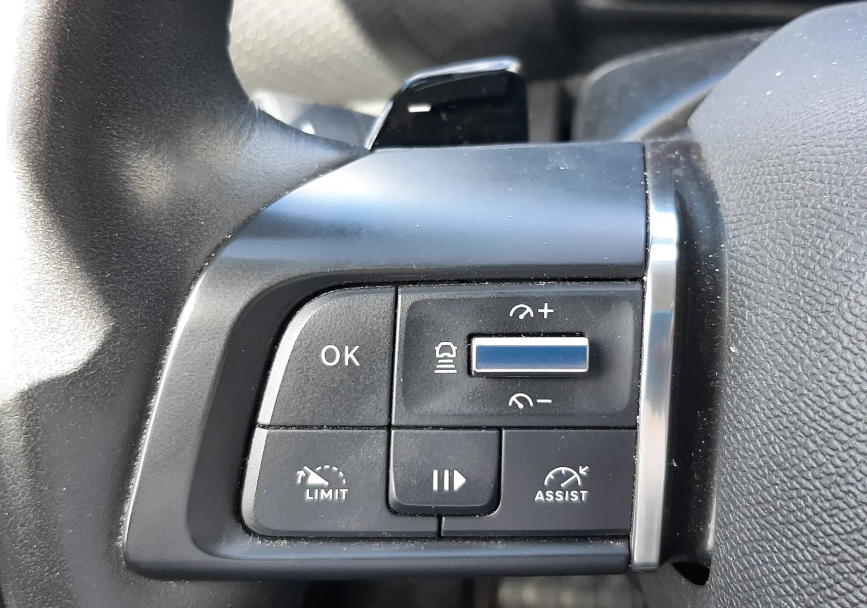 Gros plan sur les commandes au volant côté gauche d'une Citroën C4 gris 2024, avec boutons de régulateur et assistance.