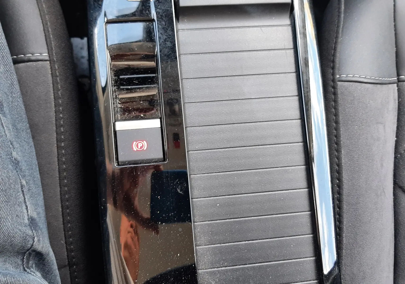 Vue rapprochée de la console centrale noire avec frein à main électronique sur Citroën C4 gris 2024.