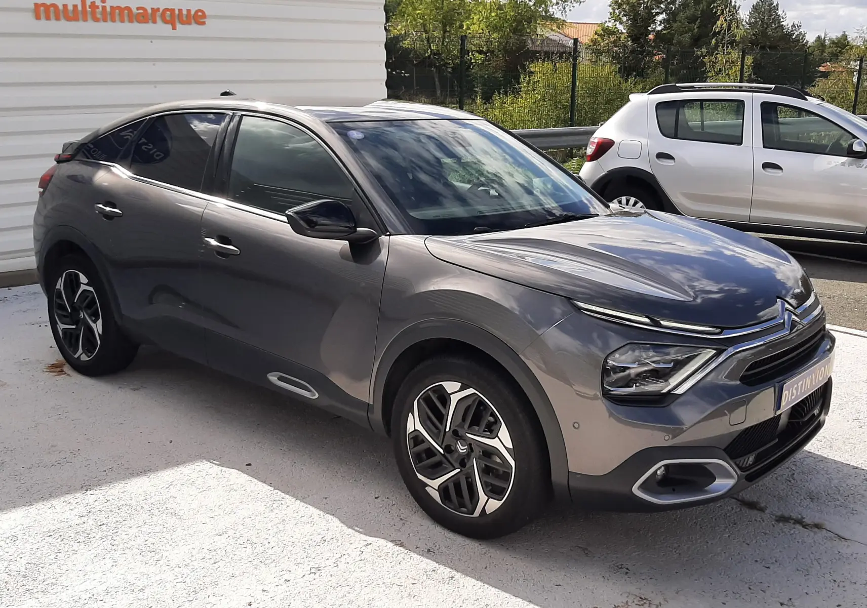 Citroën C4 gris 2024 vue 3/4 avant droit, avec jantes bi-ton et phares LED distinctifs.