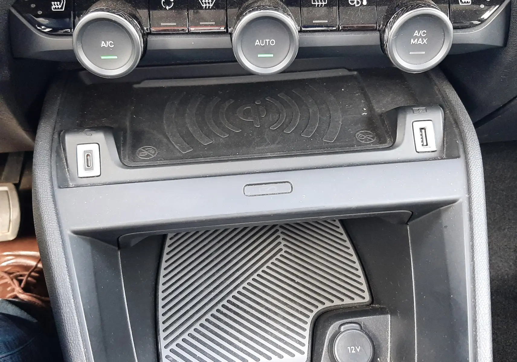 Vue rapprochée de la console centrale noire de la Citroën C4 2024, avec commandes climatisation et chargeur sans fil.