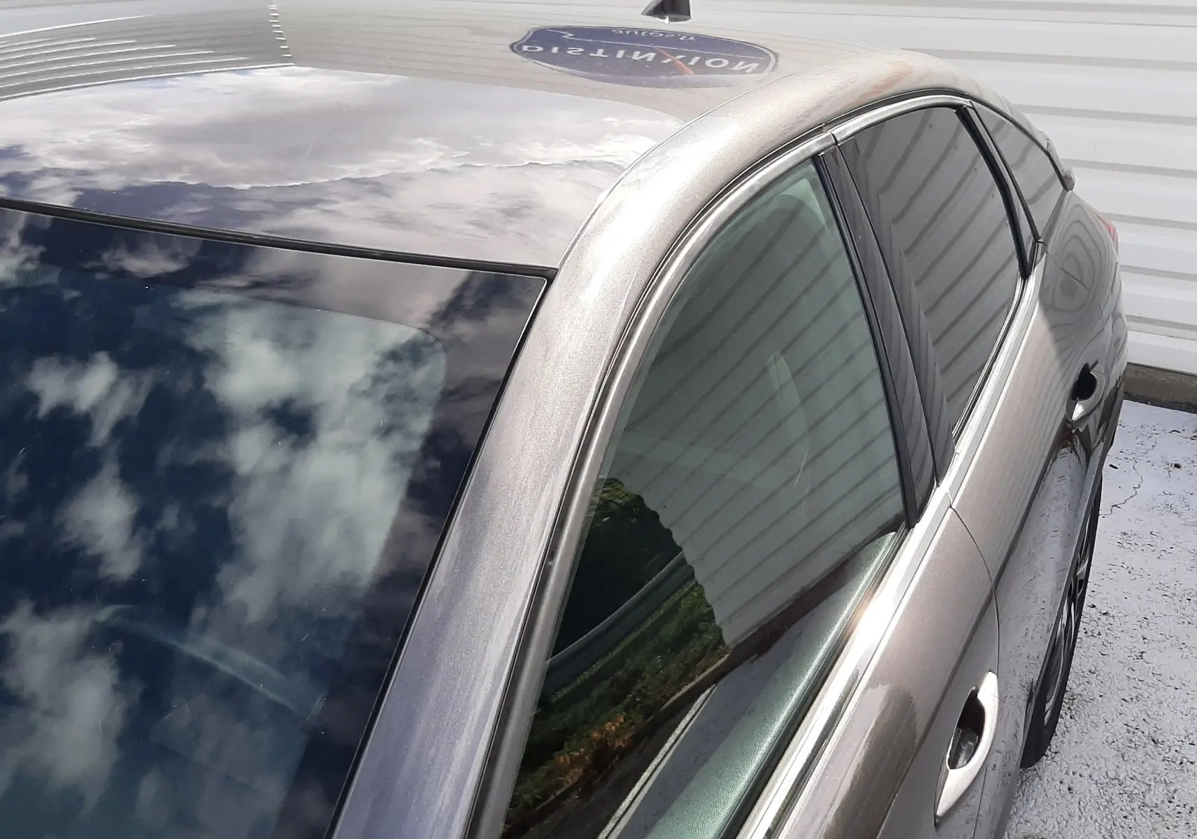 Vue en plongée côté gauche arrière d'une Citroën C4 gris métallisé avec toit panoramique et vitres teintées.