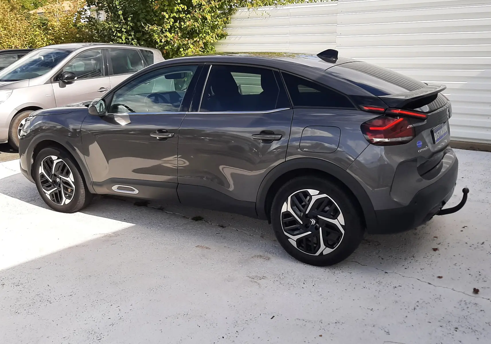 Vue latérale droite d'une Citroën C4 gris 2024 avec jantes bi-ton et toit noir, stationnée en extérieur.