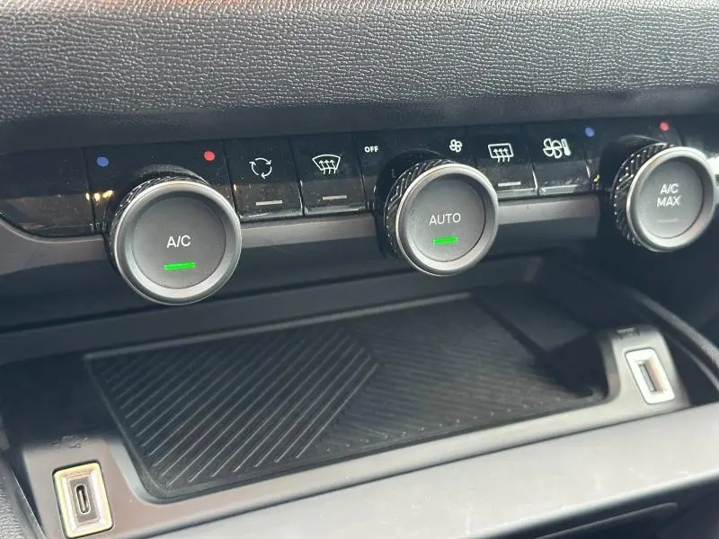 Gros plan sur les commandes de climatisation du Citroën C4 X 2025, avec boutons rotatifs et affichage lumineux vert.