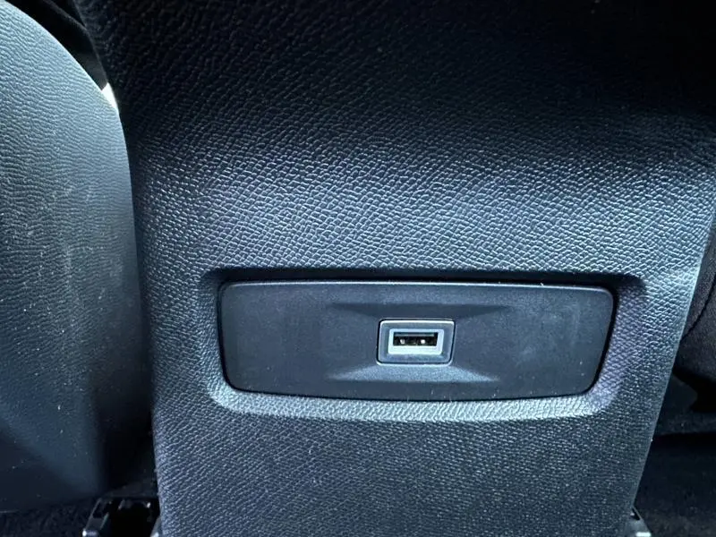 Prise USB en gros plan sur la console arrière intérieure du Citroën C4 X hybride 2025, finition noire texturée.