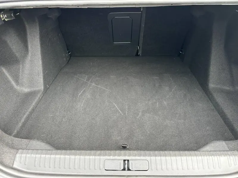 Coffre vide vu de face du Citroën C4 X 2025, revêtement intérieur gris foncé avec trappe d'accès au fond.
