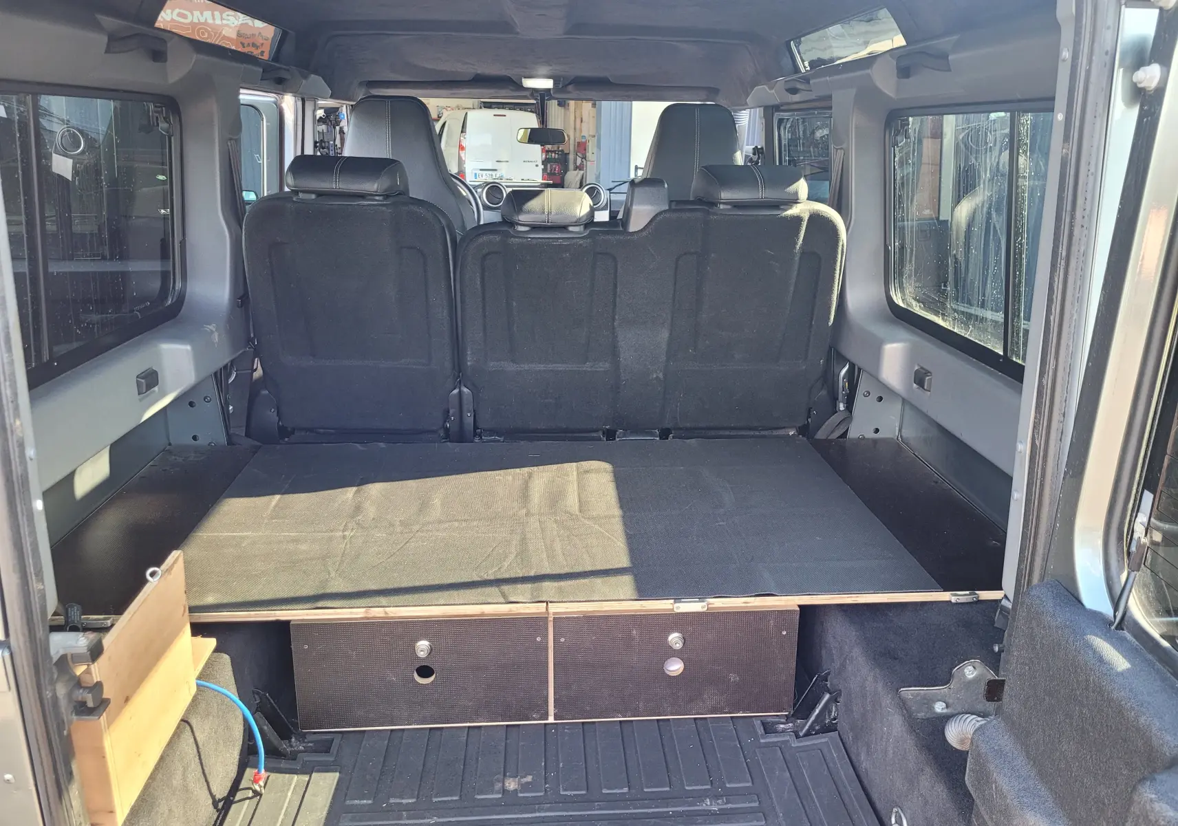 Vue arrière intérieure du Land Rover 110 Defender gris édition limitée 2015 avec aménagement de coffre plat et sièges noirs.