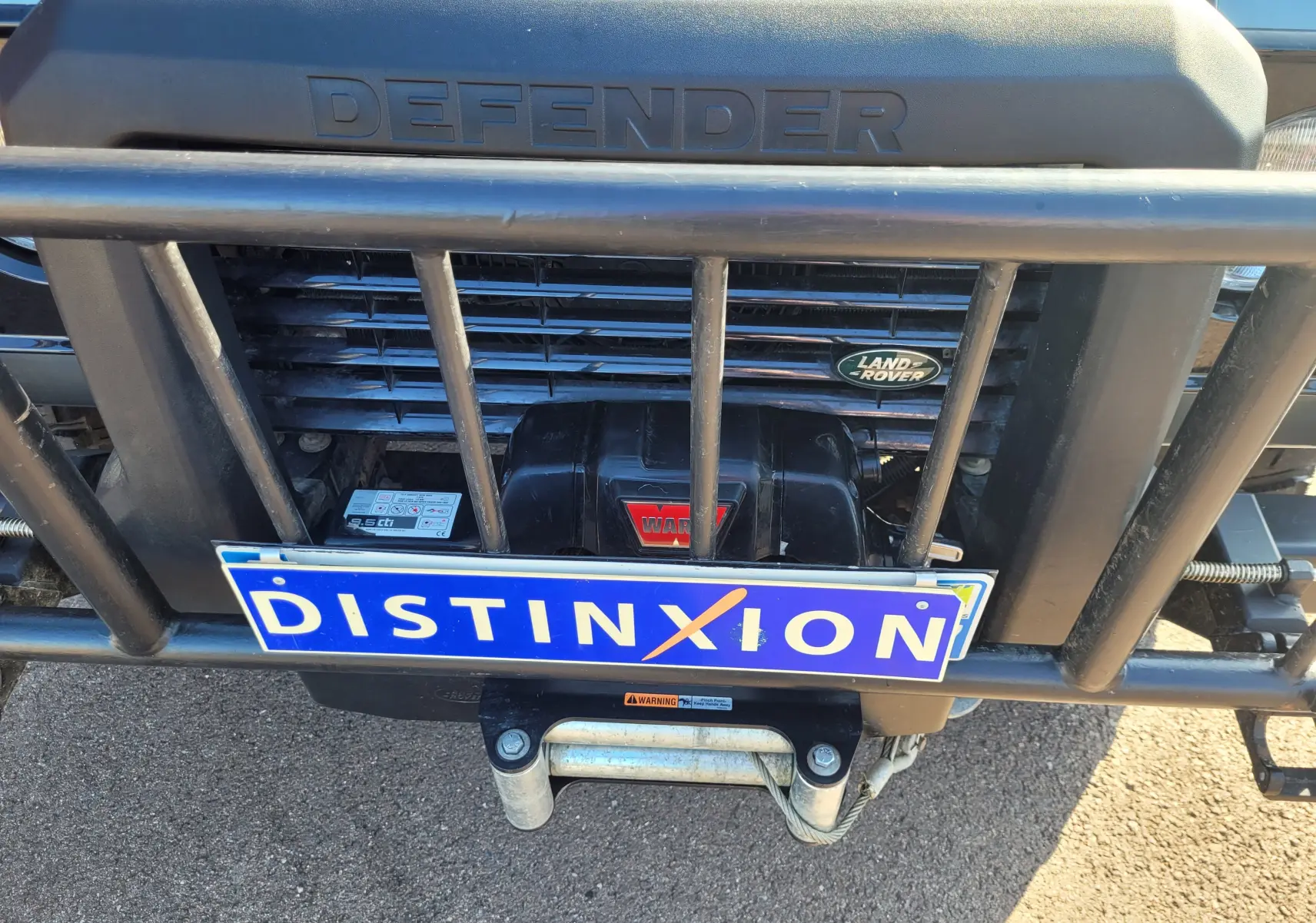 Gros plan sur la calandre avant gris foncé du Land Rover 110 Defender Edition Limiter avec treuil et barre de protection.