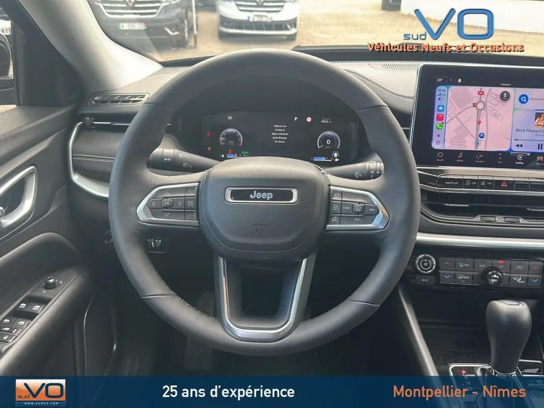 Vue intérieure centrée sur le volant Jeep Compass 2023 avec écran tactile et commandes au volant visibles.