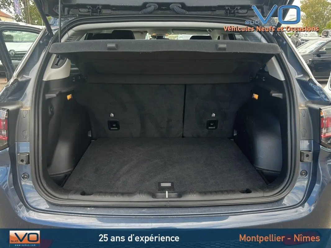 Coffre ouvert en vue arrière d'un Jeep Compass bleu 2023 avec intérieur noir et hayon relevé.