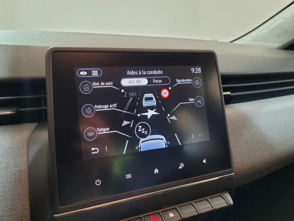 Écran tactile central affichant les aides à la conduite dans l'habitacle d'une Renault Clio gris foncé.