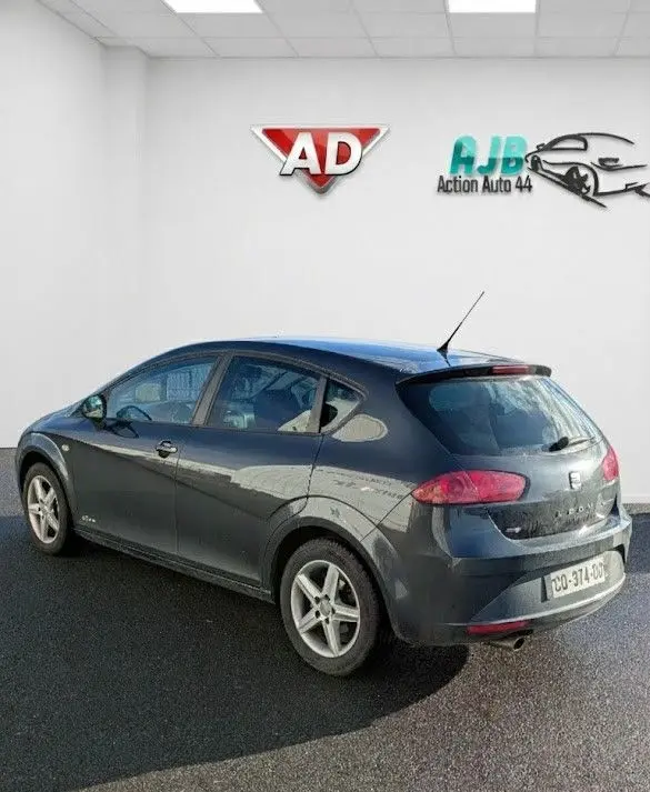 Vue 3/4 arrière droite d'une SEAT LEON II noire de 2013 avec jantes alu 16 pouces et becquet arrière.