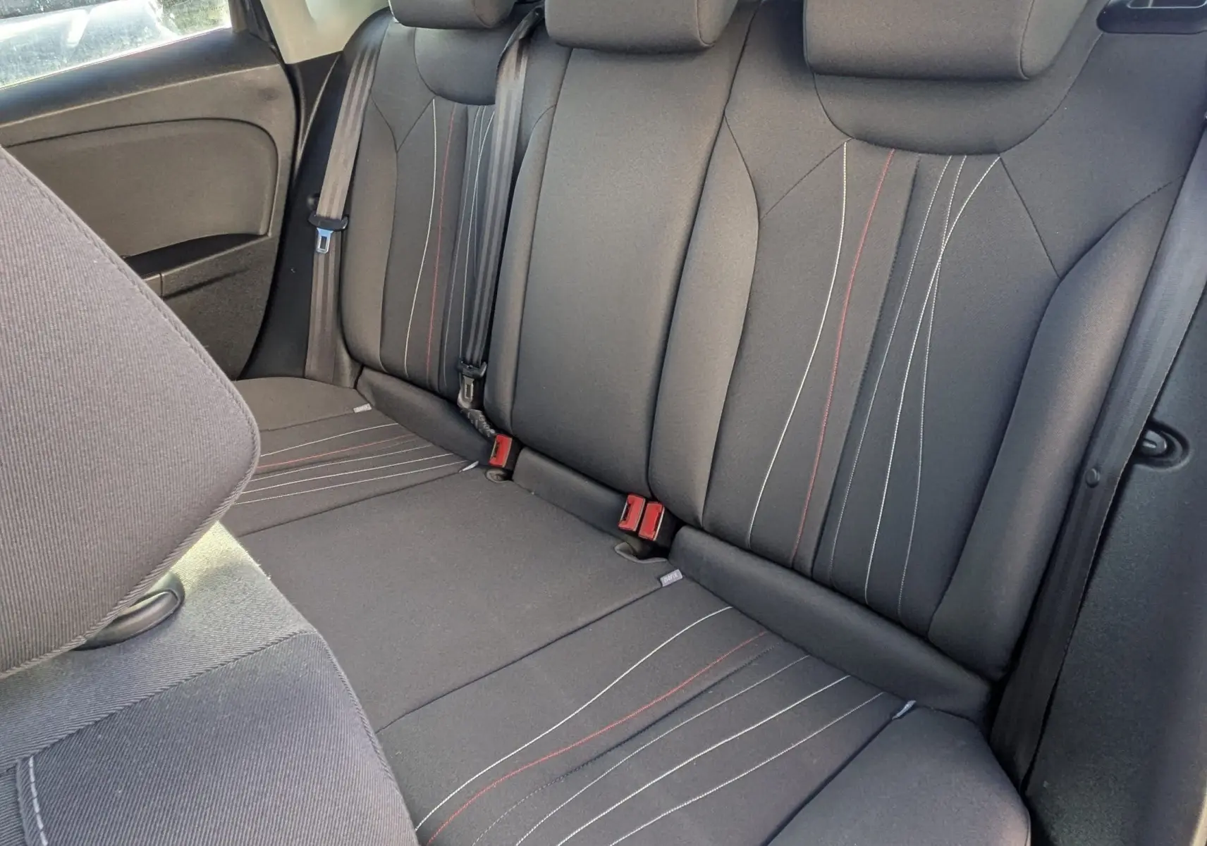 Vue intérieure de la banquette arrière noire avec appuie-têtes et surpiqûres rouges et blanches du SEAT LEON II.