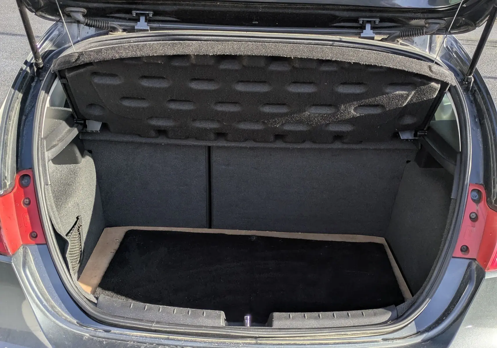 Coffre ouvert vu de l’arrière d’une SEAT LEON II noire, montrant l’espace de chargement vide et la plaque d’immatriculation.