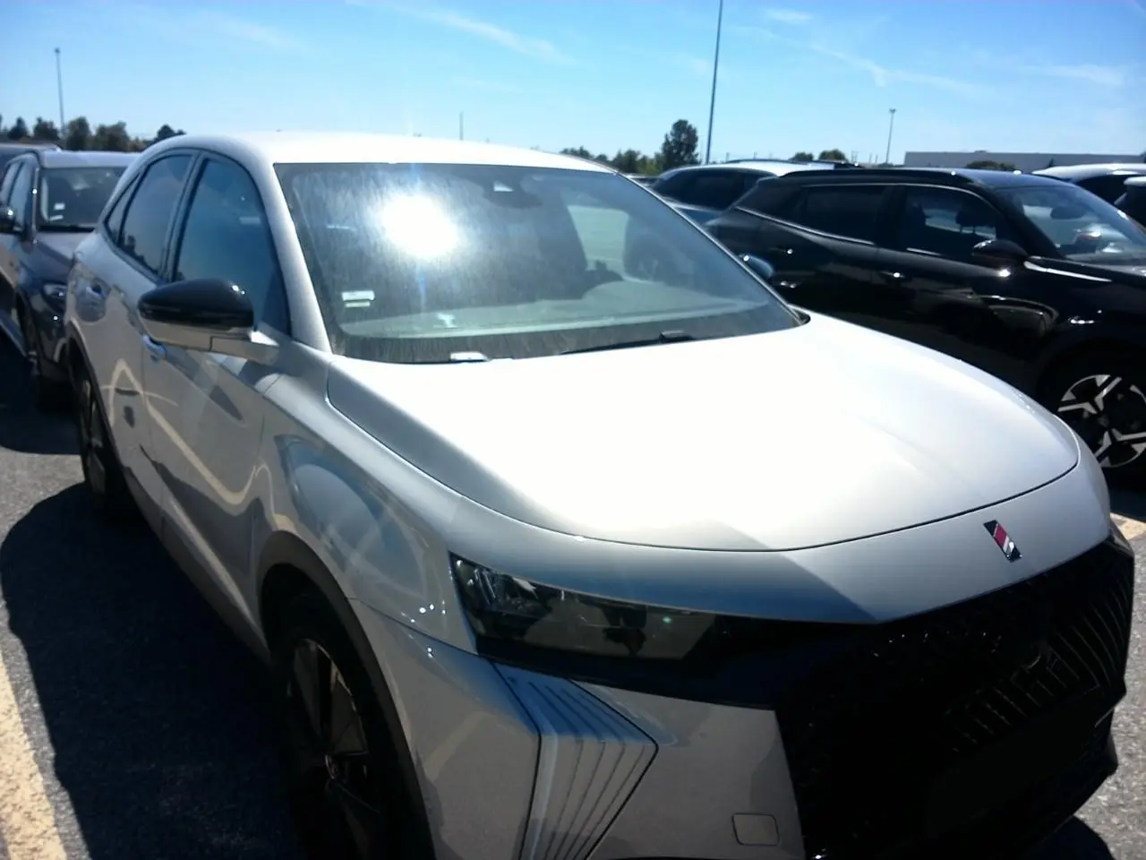 DS7 1.6 E-Tense 225 blanc Cristal Pearl en 3/4 avant gauche, avec calandre noire et jantes alliage 19 pouces.