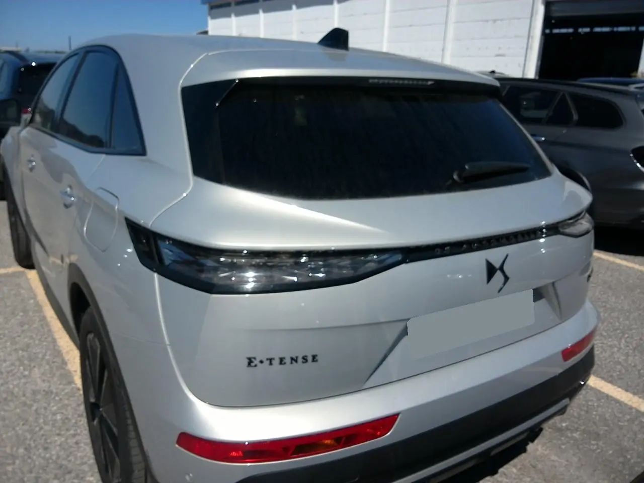 Vue 3/4 arrière du DS7 1.6 E-Tense 225 en Cristal Pearl avec feux arrière LED et logo DS distinctif.