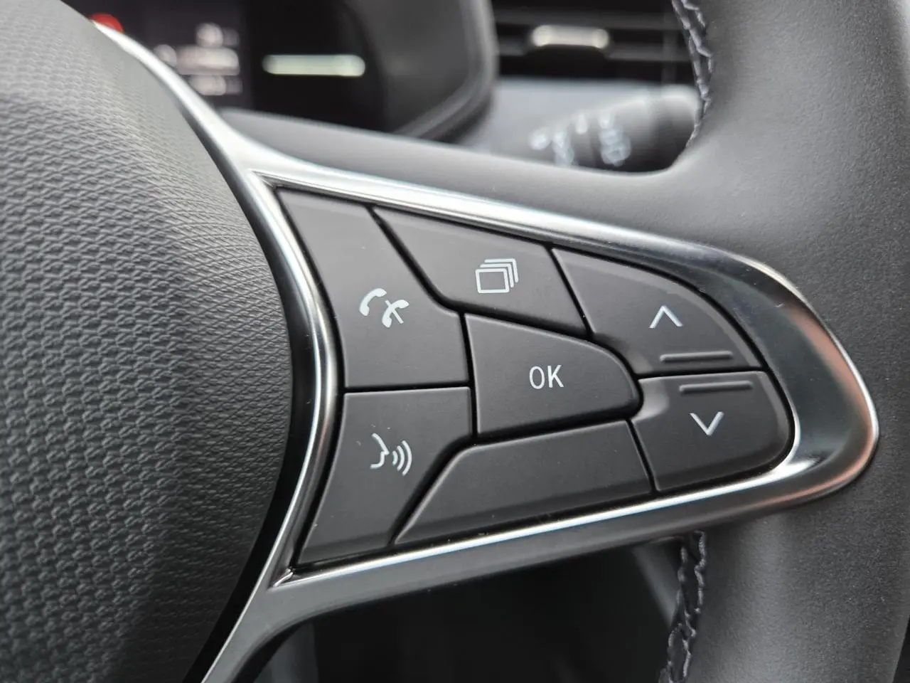Gros plan sur les commandes multifonctions noires du volant de la Renault Clio V gris schiste métal.