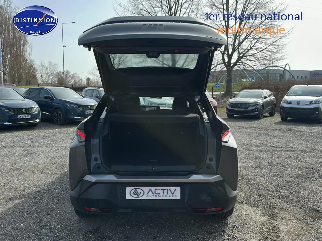 Vue arrière d'un Peugeot 3008 gris titane 2025 avec coffre ouvert sur un parking extérieur.