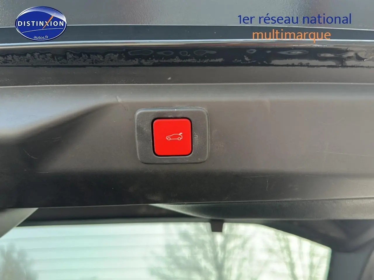 Bouton rouge d'ouverture électrique du coffre visible sur le hayon d'un Peugeot 3008 gris titane.