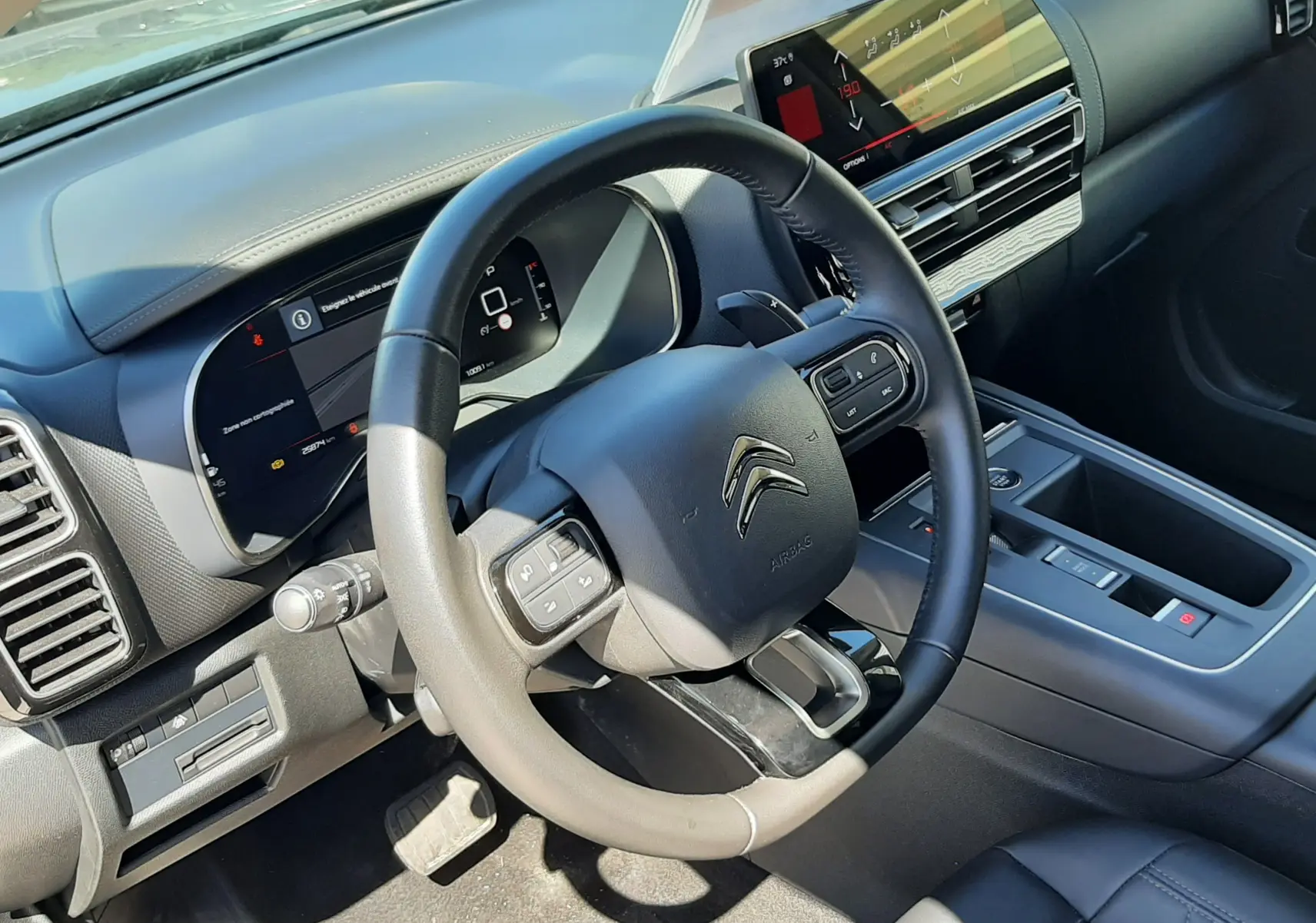 Vue intérieure côté conducteur du Citroën C5 Aircross Hybrid 136 e-DCS6 Max 2024, tableau de bord et volant noirs.