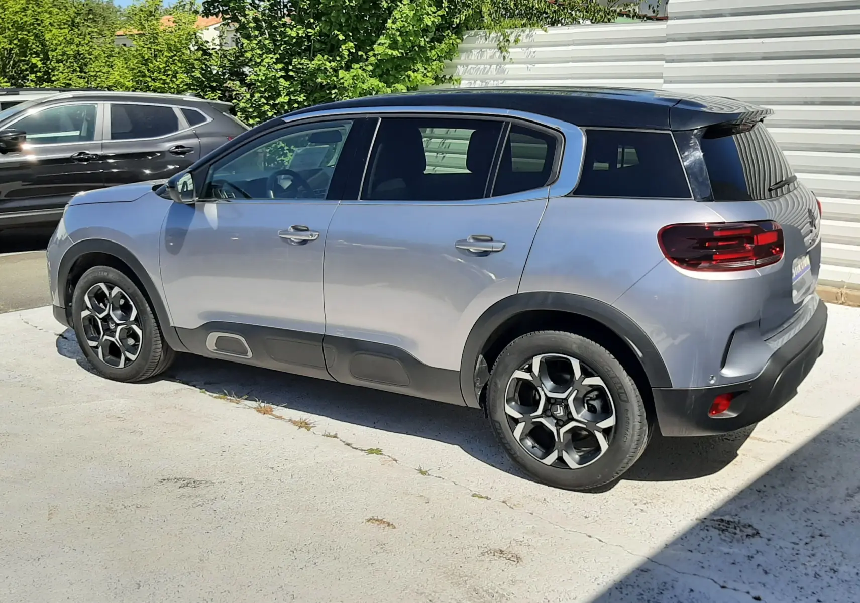 Vue de profil côté gauche du Citroën C5 Aircross Hybrid gris acier avec toit noir, roues alliage et protections latérales noires.