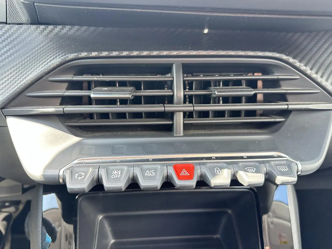 Gros plan sur la console centrale de la Peugeot 208 blanche, montrant les commandes d’air conditionné et les boutons fonctionnels.