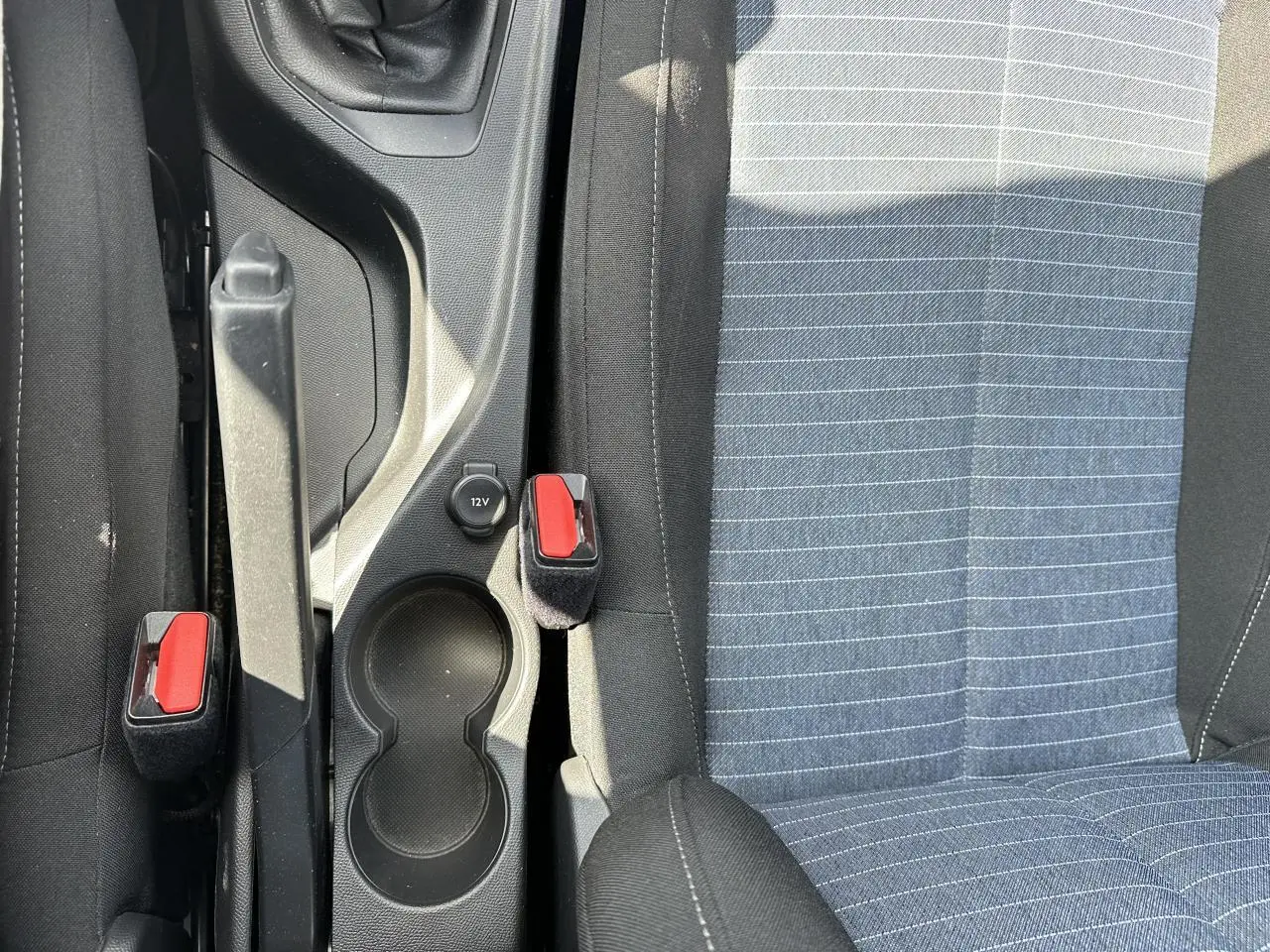 Vue rapprochée de la console centrale et des sièges avant tissu gris à rayures de la Peugeot 208 blanche.