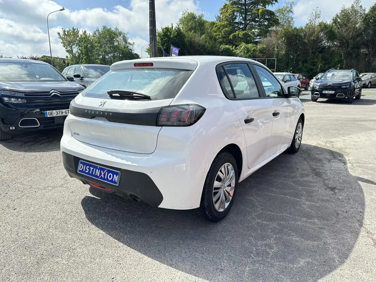 Vue 3/4 arrière droite d'une Peugeot 208 blanche 2021 avec feux arrière halogènes et jantes acier.