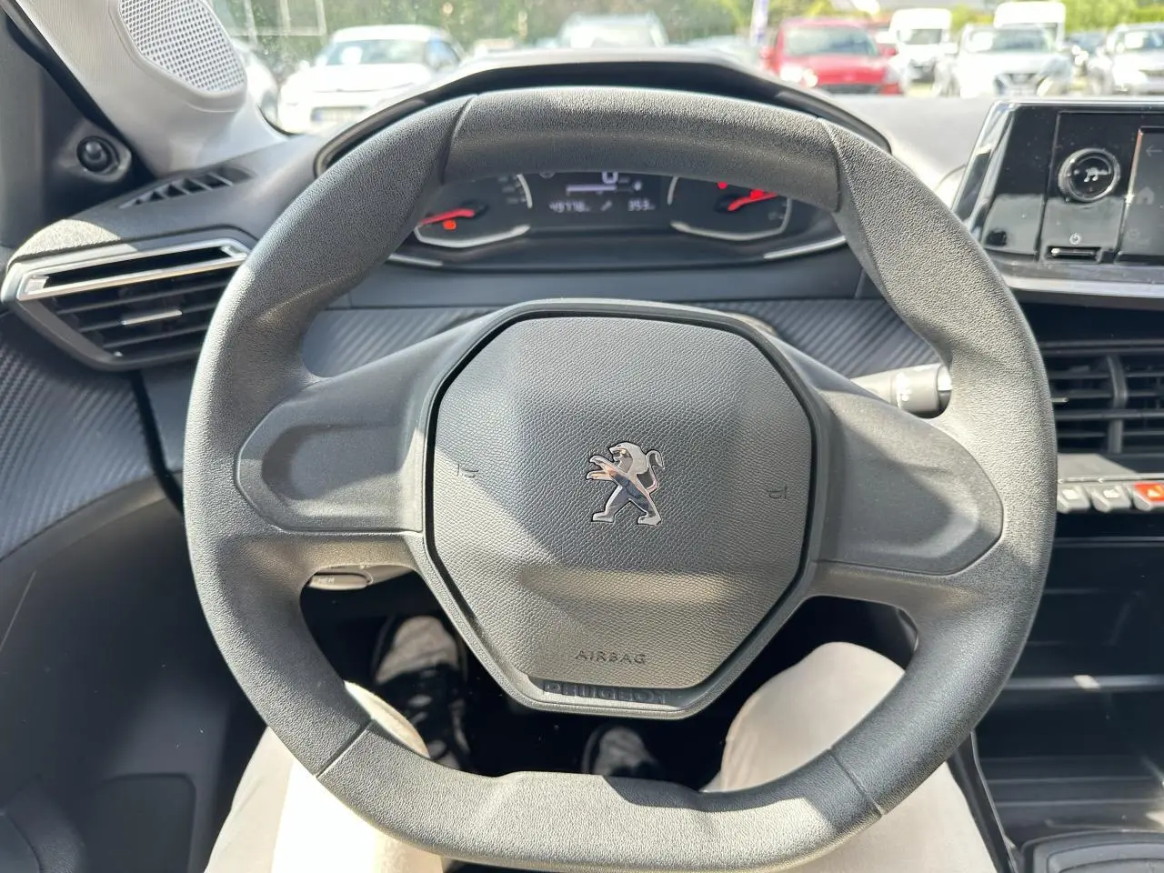Vue rapprochée du volant noir au design hexagonal du Peugeot 208 1.2i PT 75 Active 2021, intérieur moderne.