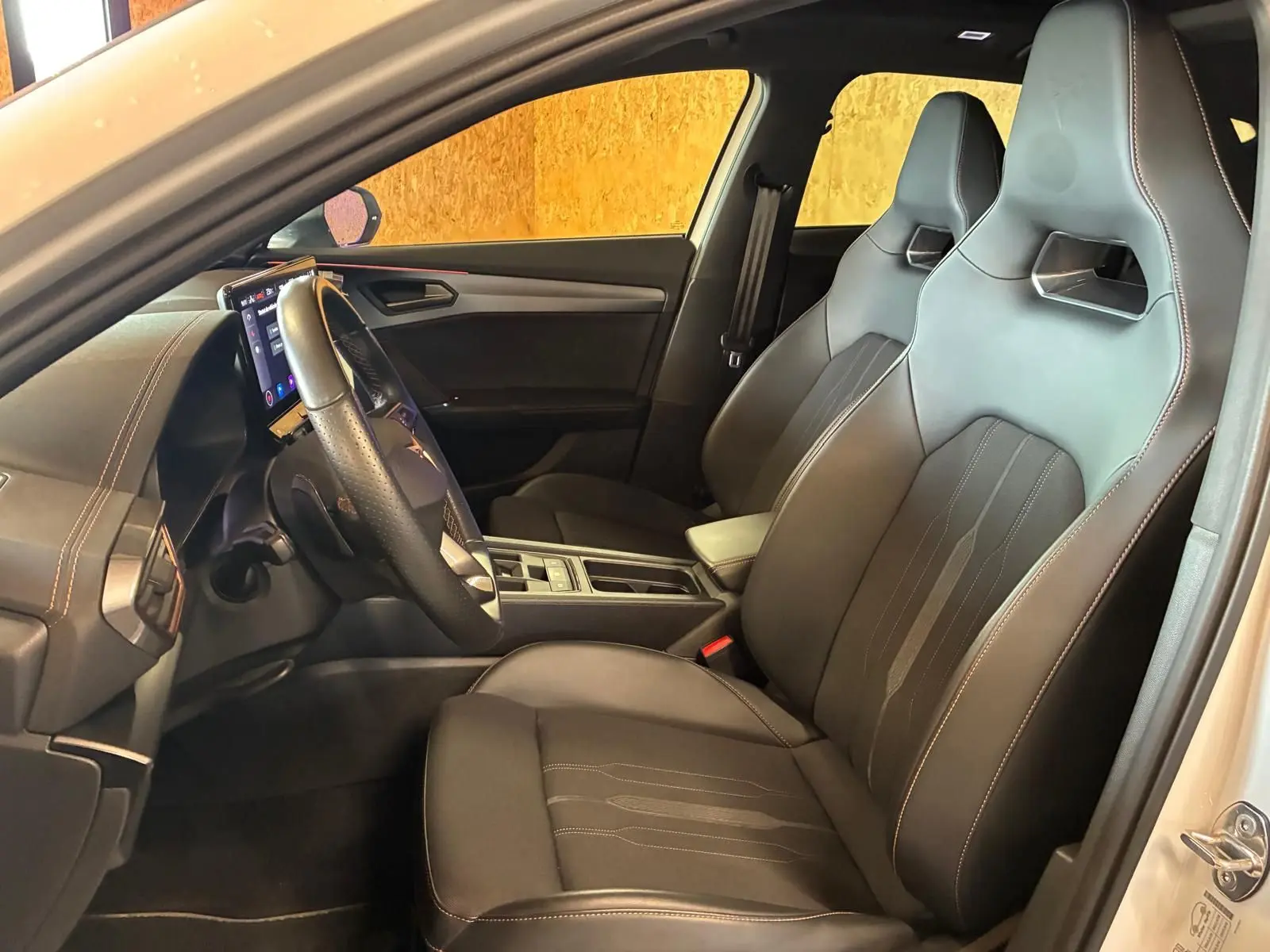 Vue intérieure côté conducteur de la CUPRA Formentor gris 2024, sièges sport en tissu noir avec surpiqûres contrastées.