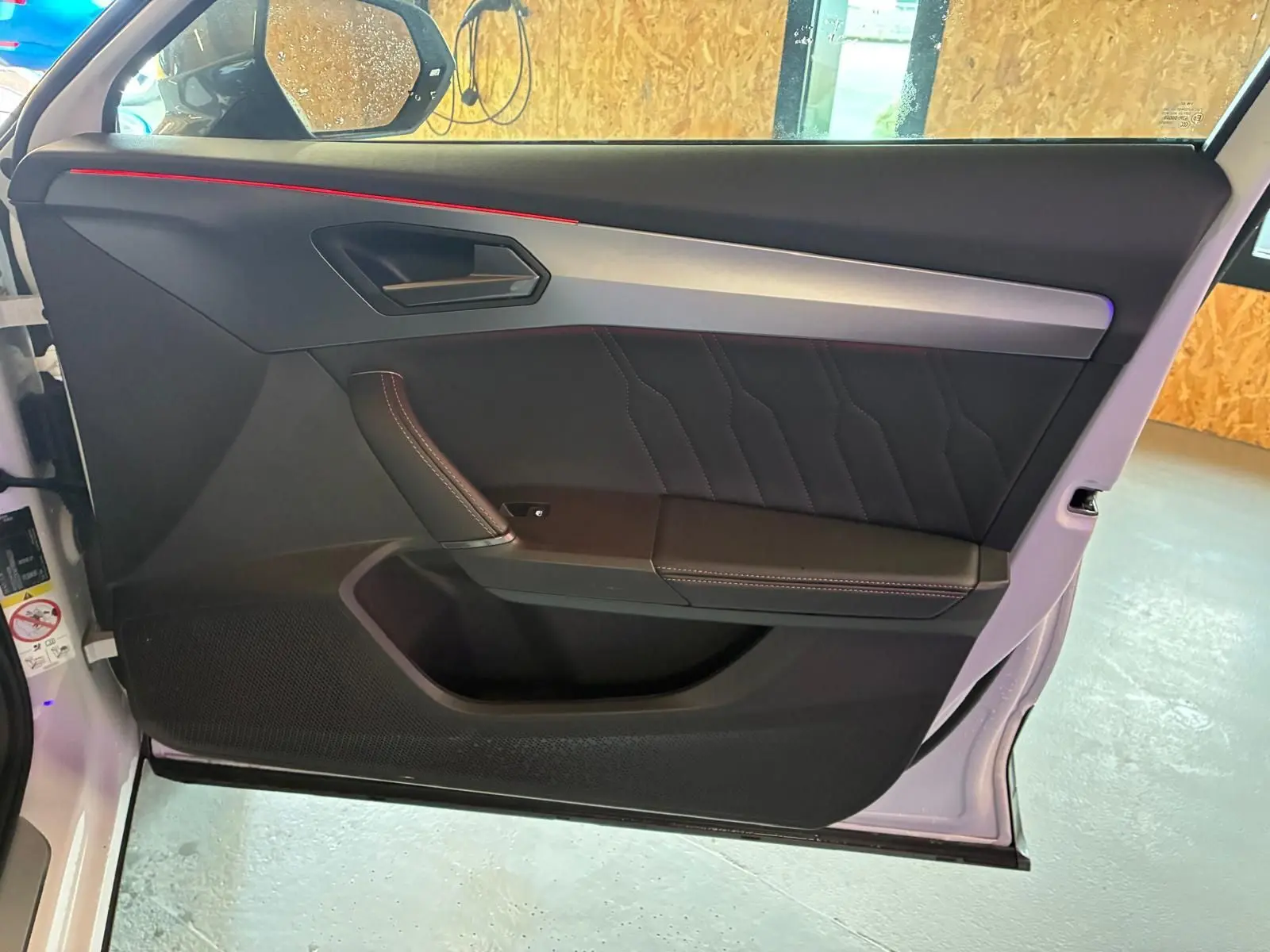 Vue intérieure de la porte avant gauche du CUPRA Formentor gris, avec surpiqûres rouges et bandeau aluminium.