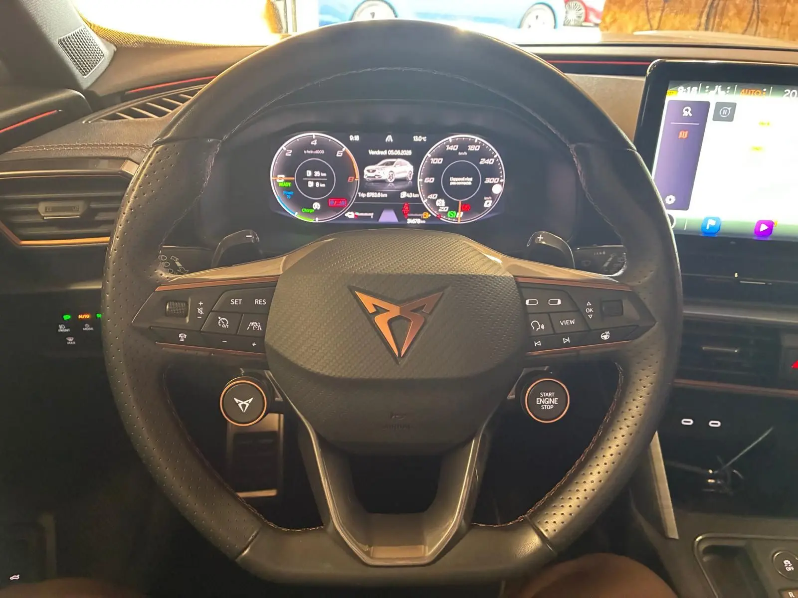 Vue rapprochée du volant noir perforé de la CUPRA Formentor 1.4 E-HYBRID 2024 avec tableau de bord numérique et écran tactile.