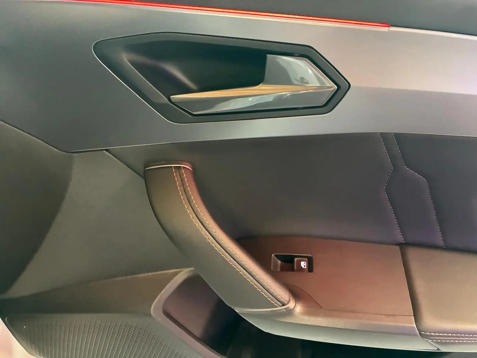 Détail de la poignée intérieure côté gauche en cuir noir avec surpiqûres sur la porte d’une CUPRA Formentor gris 2024.
