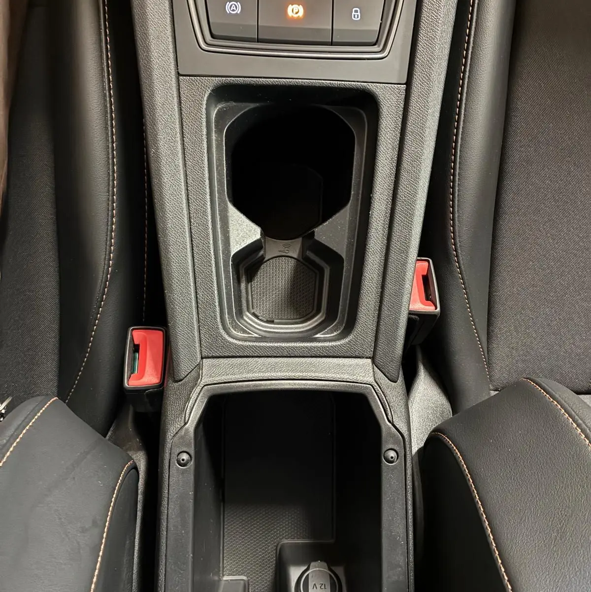 Vue plongeante sur la console centrale noire du Cupra Formentor 1.4 E-HYBRID 2024, avec porte-gobelets et prise 12V visible.