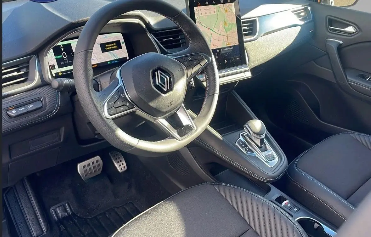 Vue intérieure côté conducteur du Renault Captur blanc nacré, volant chauffant et écran tactile central visible.