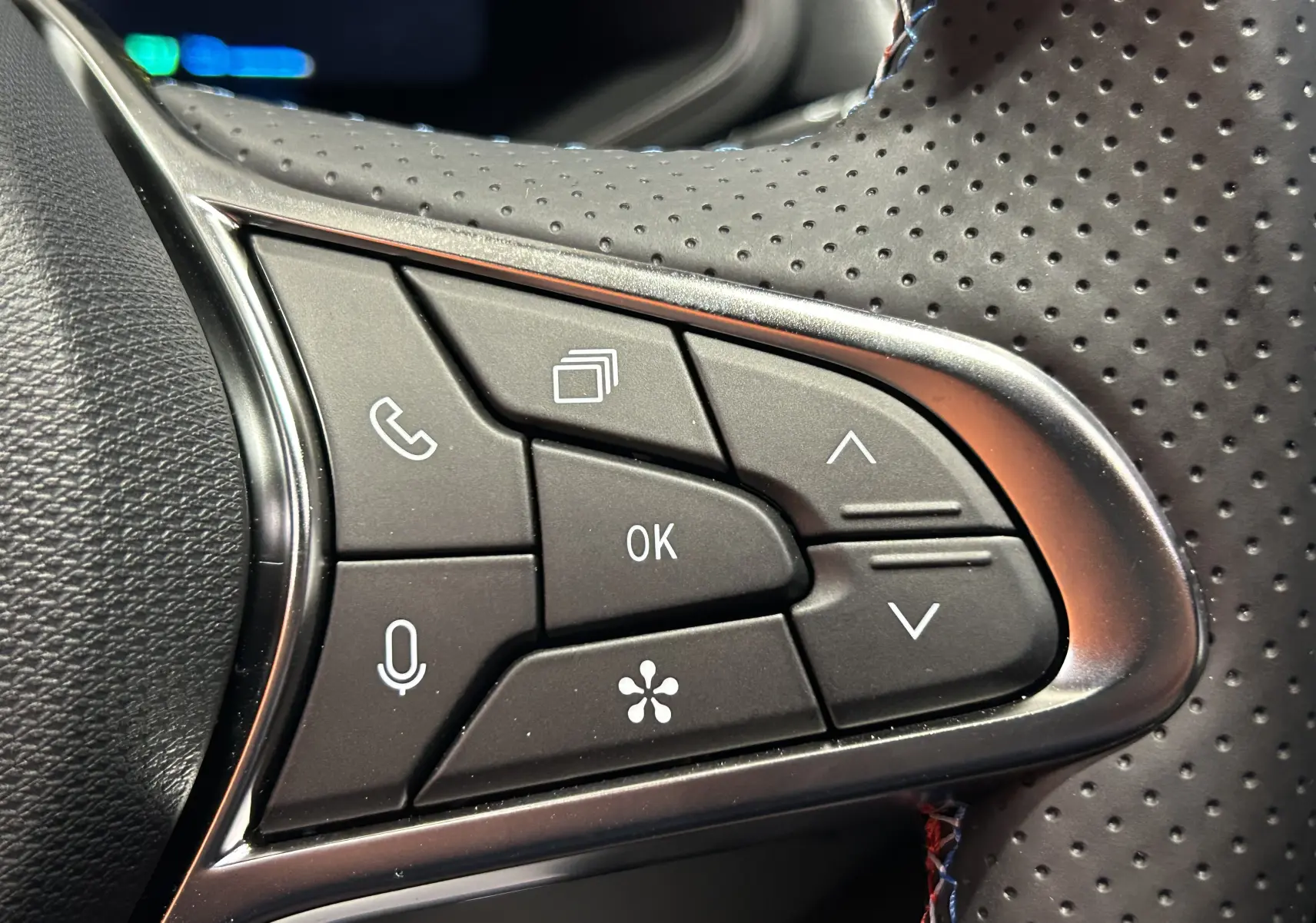 Gros plan sur les commandes multifonctions du volant perforé du Renault Captur blanc nacré, version hybride 2026.