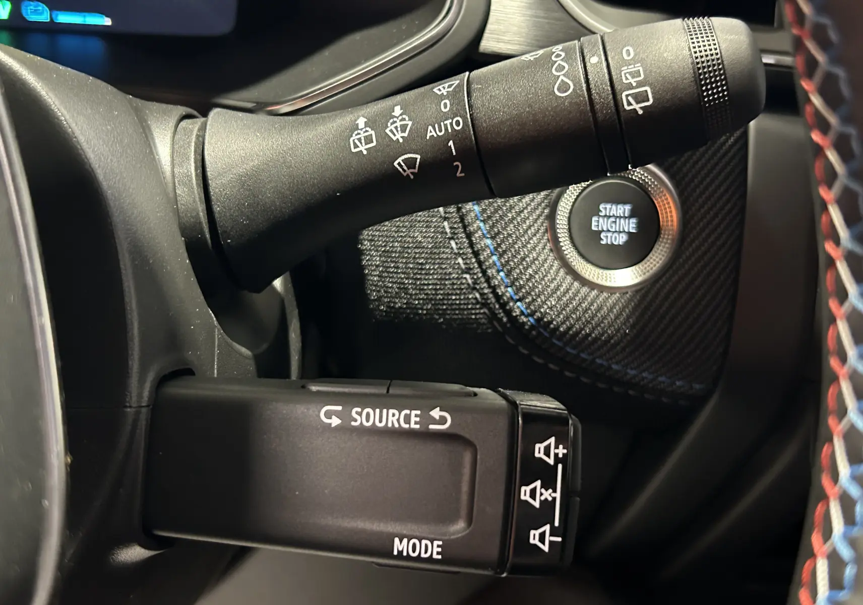 Détail intérieur du Renault Captur blanc nacré montrant la commande d’essuie-glace et le bouton Start Engine Stop.