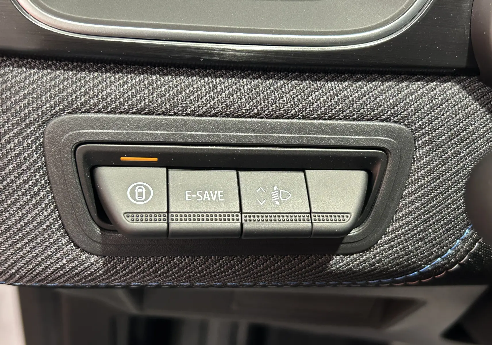Gros plan sur les boutons de commande E-SAVE et réglage des phares dans l’habitacle du Renault Captur blanc nacré 2026.