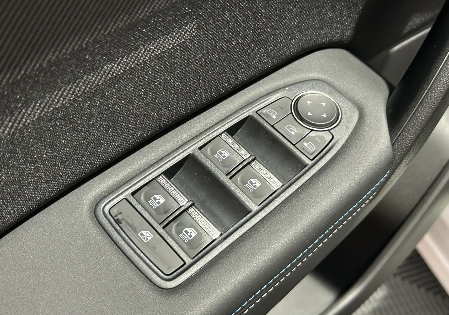 Gros plan sur les commandes de lève-vitres et rétroviseurs côté conducteur du Renault Captur blanc nacré 2026.