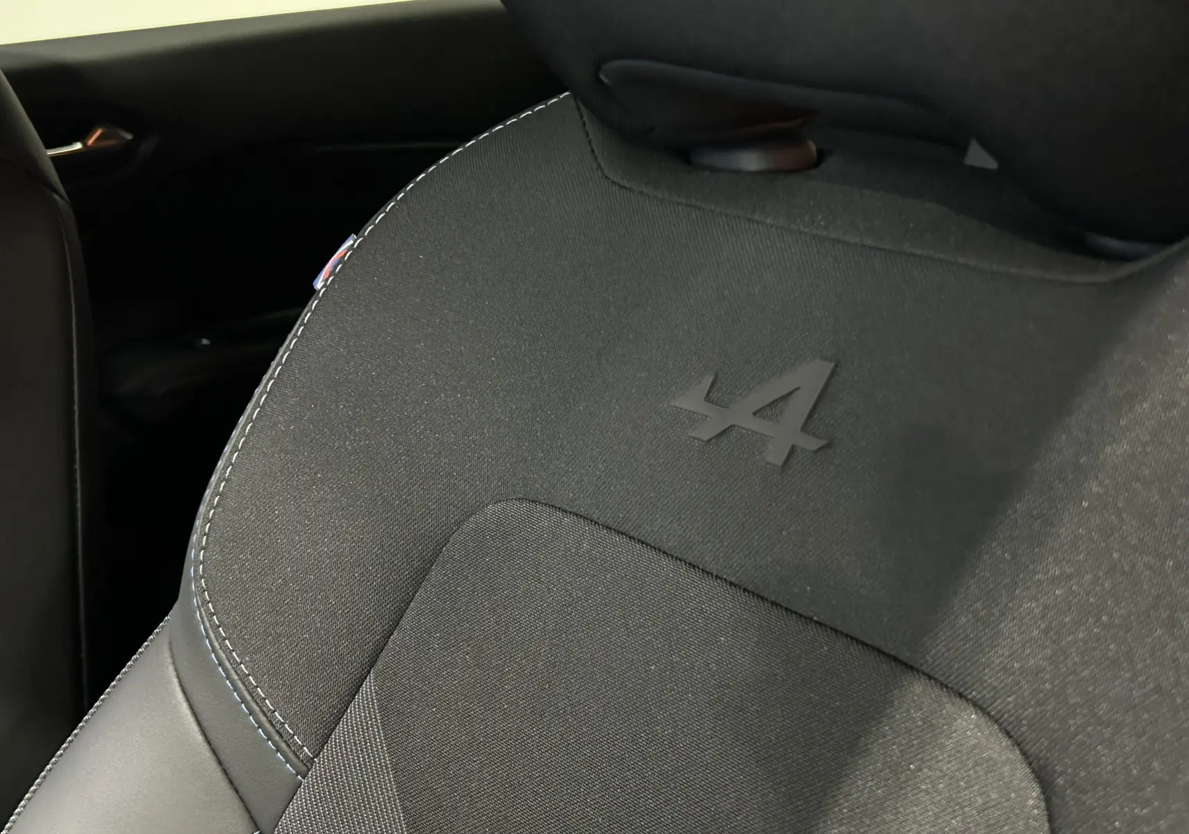 Détail du siège avant noir avec logo Alpine embossé, intérieur du Renault Captur II Ph.2 blanc nacré.