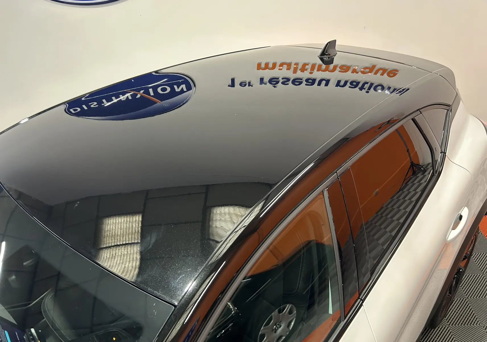 Vue plongeante sur le toit noir brillant et la carrosserie blanc nacré du Renault Captur II Ph.2 hybride.